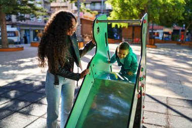Mother and son playing on slide at park