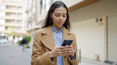 Sokakta gülümseyen akıllı telefon kullanan genç, güzel İspanyol kadın.