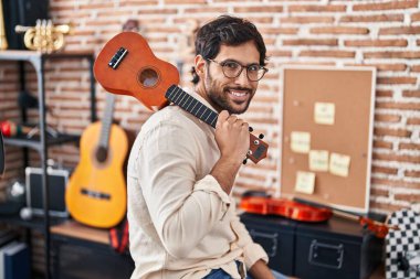Genç İspanyol müzisyen müzik stüdyosunda ukulele tutuyor.
