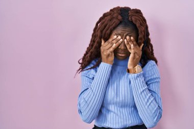 Pembe arka planda duran Afrikalı kadın yorgunluk ve baş ağrısı için gözlerini ovuşturuyor, uykulu ve yorgun ifade. görme sorunu 