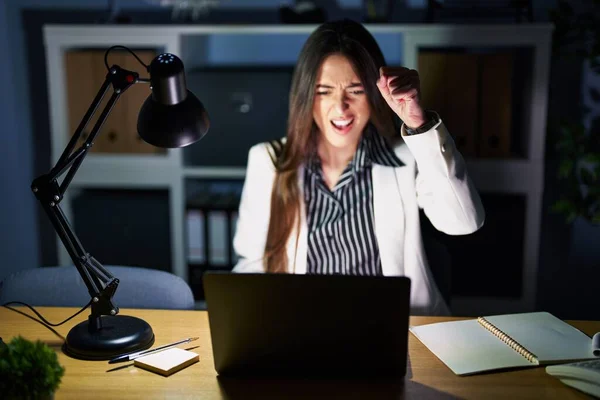 Молодая Брюнетка Работающая Ночью Офисе Ноутбуком Злая Безумная Поднимающая Кулак — стоковое фото