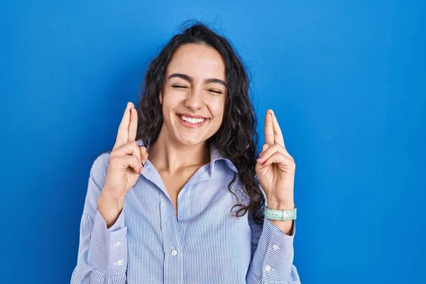 Jovem Morena Sobre Fundo Azul Gesto Dedo Cruzado Sorrindo Com — Fotografia de Stock