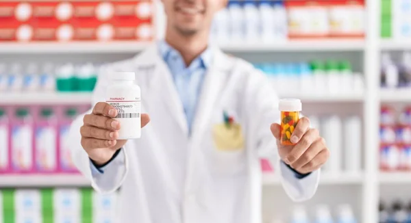 Young Hispanic Man Pharmacist Smiling Confident Holding Pills Bottles Pharmacy — Stock fotografie