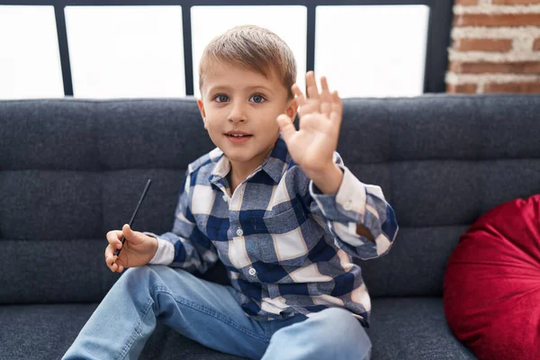 Liebenswerter Kaukasischer Junge Grüßt Mit Einer Hand Auf Dem Sofa — Stockfoto