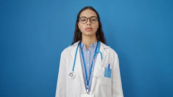 年轻美丽的惊慌失措的女医生站在那里 严肃而严肃地面对着孤独的蓝色背景 — 图库照片