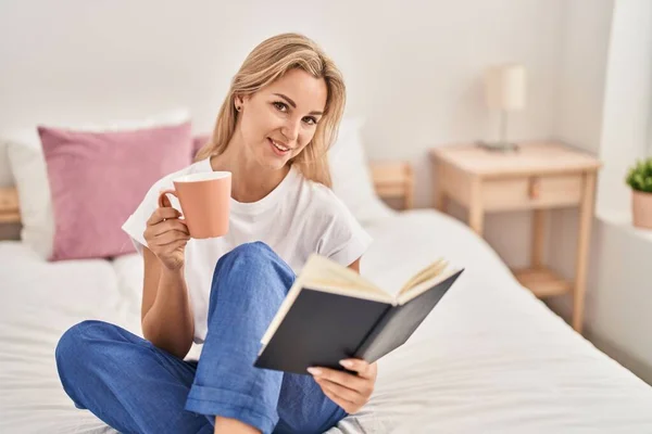 Νεαρή Ξανθιά Γυναίκα Πίνει Καφέ Διαβάζοντας Βιβλίο Στο Υπνοδωμάτιο — Φωτογραφία Αρχείου