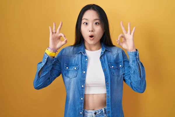 Mladá Asiatka Stojí Nad Žlutým Pozadím Vypadá Překvapeně Šokovaně Když — Stock fotografie