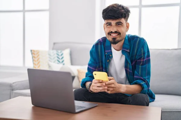 Young Hispanic Man Using Laptop Smartphone Sitting Sofa Home — Fotografia de Stock