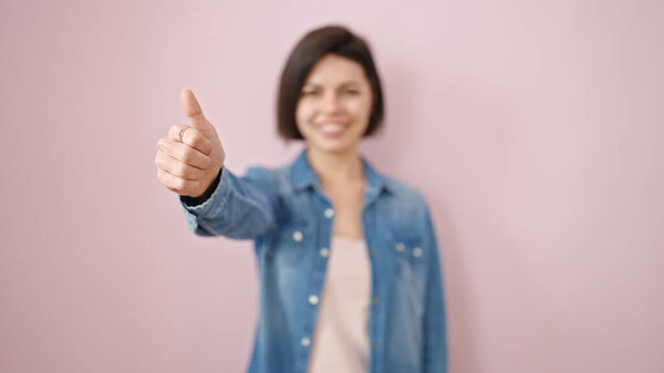 Young caucasian woman smiling with thumbs up over isolated pink background