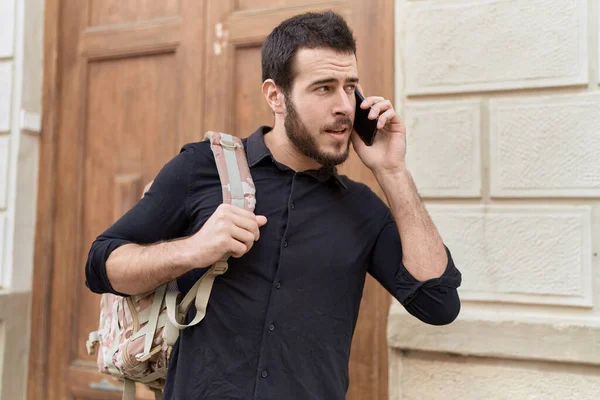 在街上用智能手机说话的年轻人背着背包 — 图库照片
