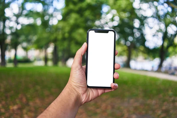 Mężczyzna Gospodarstwa Smartfon Pokazując Biały Pusty Ekran Parku — Zdjęcie stockowe