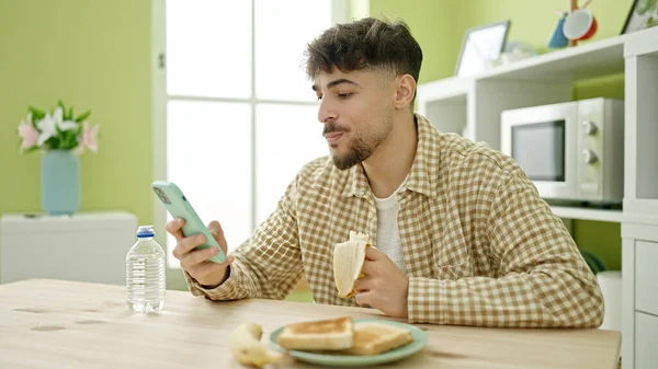 Hombre Árabe Joven Desayunando Usando Smartphone Casa — Foto de Stock