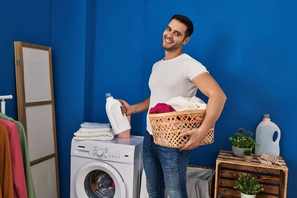 Young Hispanic Man Holding Basket Clothes Detergent Bottle Laundry Room — Stock Photo, Image