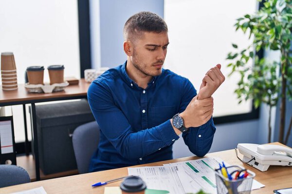 Young hispanic man business worker suffering for wrist pain at office