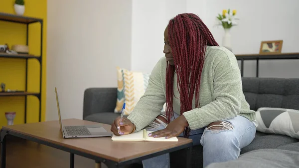自宅でノートパソコンの書き込みを使用して編組髪を持つアフリカの女性 — ストック写真