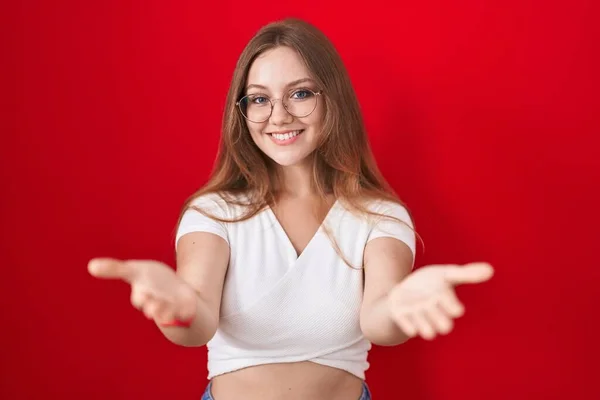 Joven Mujer Caucásica Pie Sobre Fondo Rojo Sonriente Alegre Ofreciendo —  Fotos de Stock