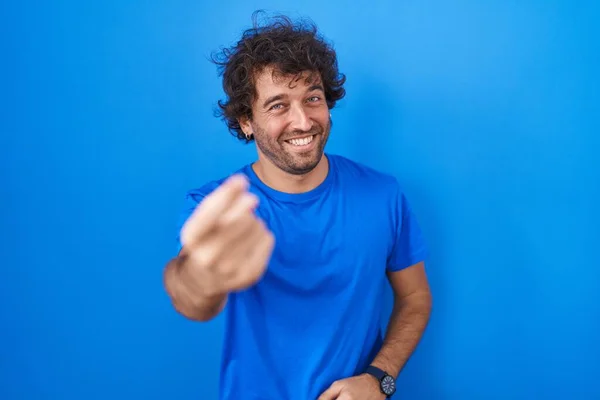 西班牙裔年轻人站在蓝色的背景上招呼着 手拉着欢迎快乐和微笑来到这里 — 图库照片