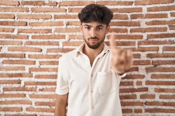 髭を生やしたアラブ人がレンガの壁の上に立ち 指を上げて怒りの表情をしている — ストック写真