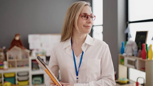 Young Blonde Woman Preschool Teacher Smiling Confident Holding Books Kindergarten — Foto Stock