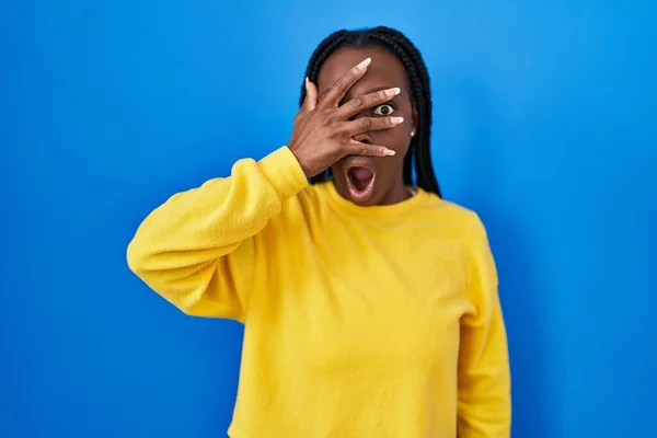 Mooie Zwarte Vrouw Staan Blauwe Achtergrond Gluren Shock Bedekking Gezicht — Stockfoto
