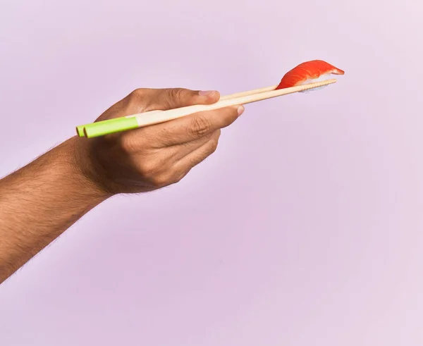 人类的手拿着用筷子包裹着孤立的粉色背景的大虾黑鬼 — 图库照片