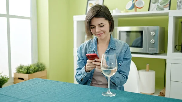 若い白人女性が自宅でスマートフォンのワインを飲む — ストック写真