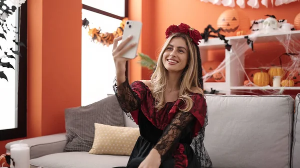 Young blonde woman making selfie by smartphone having halloween party at home