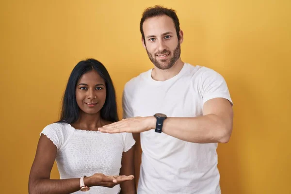 Interracial Couple Standing Yellow Background Gesturing Hands Showing Big Large — Stock Photo, Image