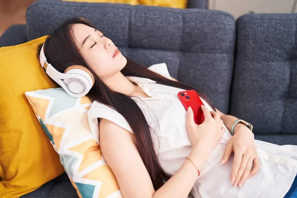 Young Chinese Woman Listening Music Sleeping Sofa Home — Stockfoto