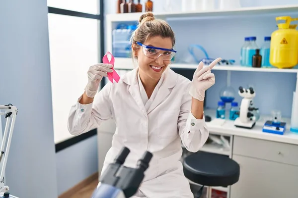Молодая Женщина Работающая Научной Лаборатории Держа Розовую Ленту Улыбаясь Счастливо — стоковое фото