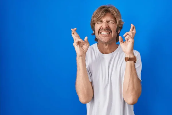 Homem Meia Idade Sobre Fundo Azul Gesto Dedo Cruzado Sorrindo — Fotografia de Stock
