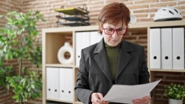 Olgun İspanyol kadın iş adamı ofiste belge okuyor.