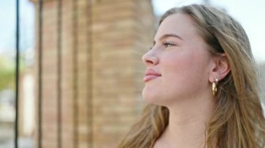 Young blonde woman breathing with closed eyes at street