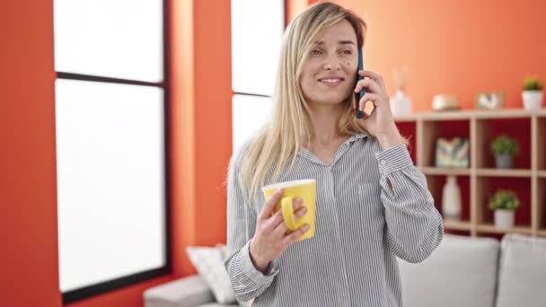 Junge Blonde Frau Trinkt Kaffee Und Telefoniert Hause Mit Dem — Stockvideo