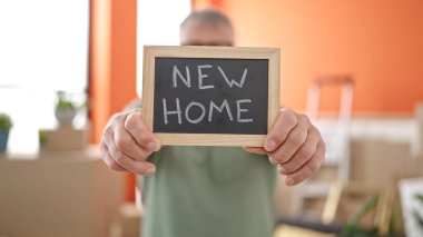 Orta yaşlı, kır saçlı bir adam yeni evinde karatahta tutuyor.