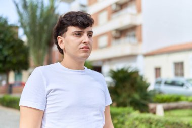 İkili olmayan adam parkta ciddi bir ifadeyle duruyor.