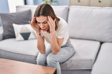 Evdeki kanepede oturan güzel İspanyol kadın baş ağrısı çekiyor.