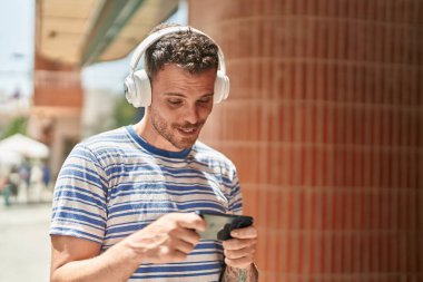 Young hispanic man smiling confident playing video game at street