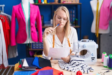 Genç sarışın kadın dikiş atölyesinde doküman okuyor.