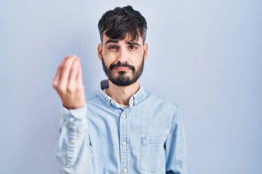 Mavi arka planda sakallı genç İspanyol bir adam el ve parmakları ile italyan jestleri yapıyor. 