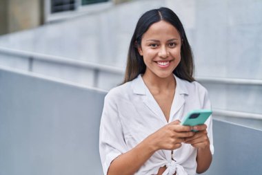 Sokakta akıllı telefon kullanan, kendine güvenen genç İspanyol kadın.