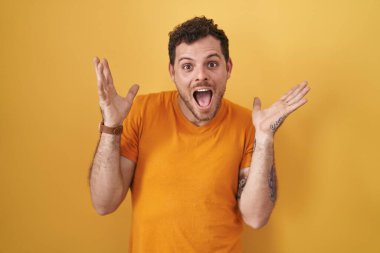 Sarı arka planda duran genç İspanyol adam çılgın ve başarıyı kollarını kaldırıp heyecanla haykırarak kutluyor. Kazanan konsept 