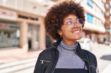 Afro-Amerikalı kadın gülümsüyor. Kendine güveniyor. Gökyüzüne bakıyor.