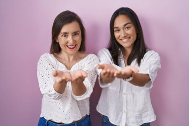 Elleri avuçlarında gülümseyen İspanyol anne ve kız jest yapıyor ya da yapıyor. Bekleme ve koruma 