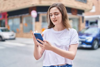 Sokakta akıllı telefon kullanan kendine güvenen genç bir kadın.