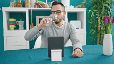 İspanyol adam yemek odasında masada oturmuş şarap içiyor.