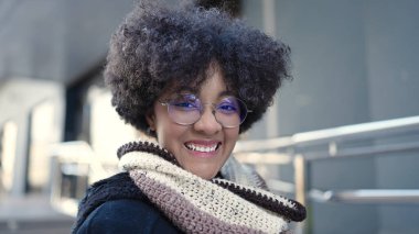 Sokakta kendinden emin gülümseyen Afrikalı Amerikalı genç bir kadın.