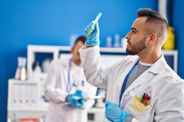 Two men scientists writing on document holding test tube at laboratory