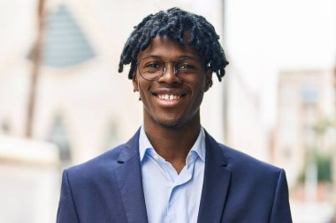 Afro-Amerikalı yönetici gülümseyerek caddede duruyor.