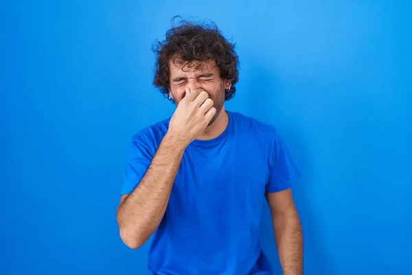 Jovem Hispânico Sobre Fundo Azul Cheirando Algo Fedorento Nojento Cheiro — Fotografia de Stock
